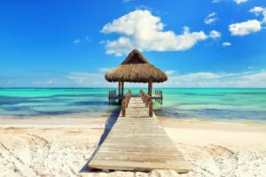 Tropical white sandy beach. Palm leaf roofed wooden pier with gazebo on the beach. Cross processed. Instagram filter. Punta Cana, Dominican Republic