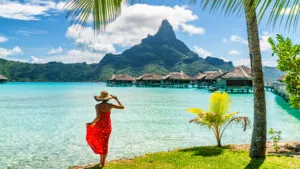 Tahiti travel holiday luxury hotel vacation tourist woman walking on Bora Bora island beach with view of Mt Otemanu in French Polynesia. High end resort with overwater bungalows villas.